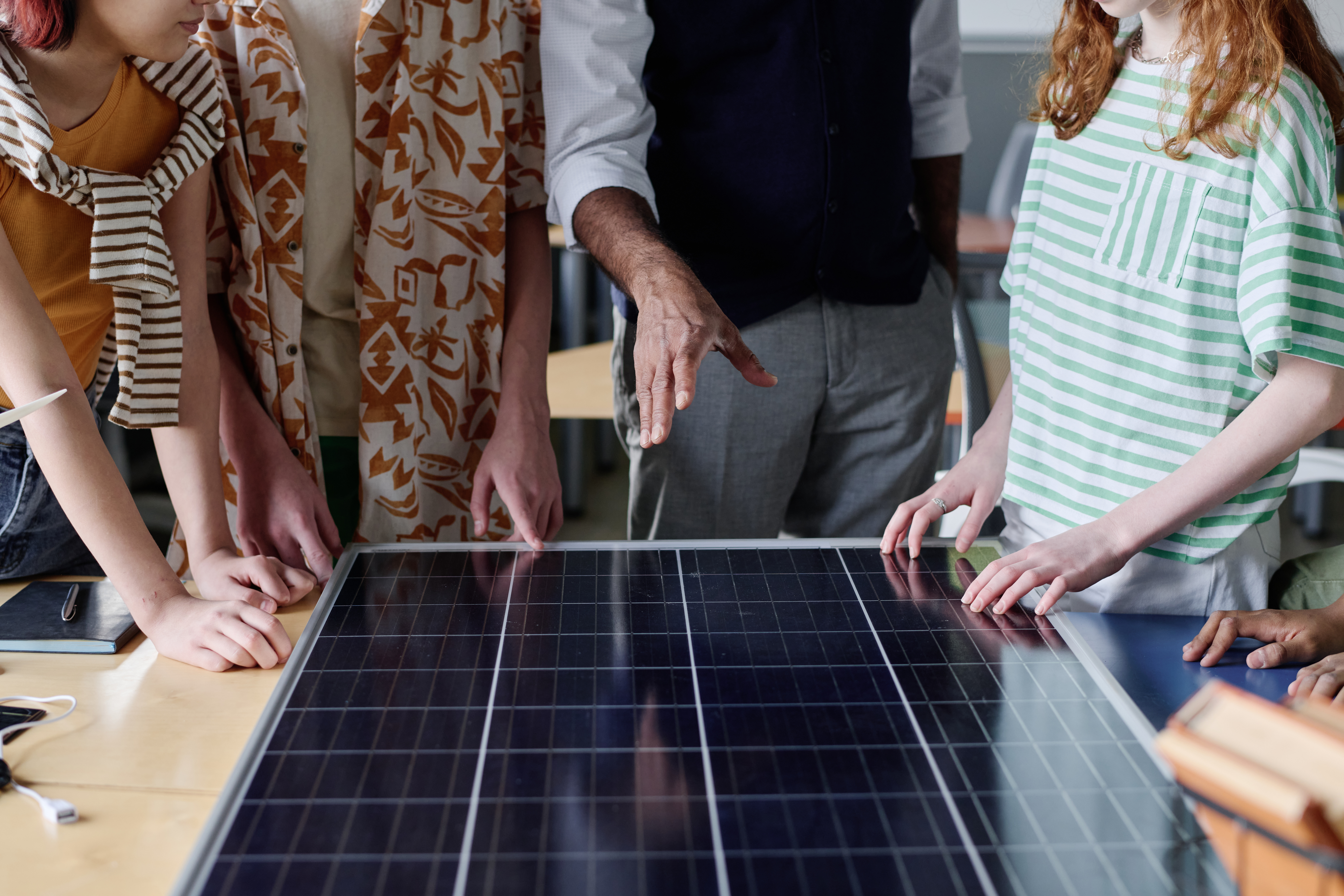 A group of people huddle around a solar panel model