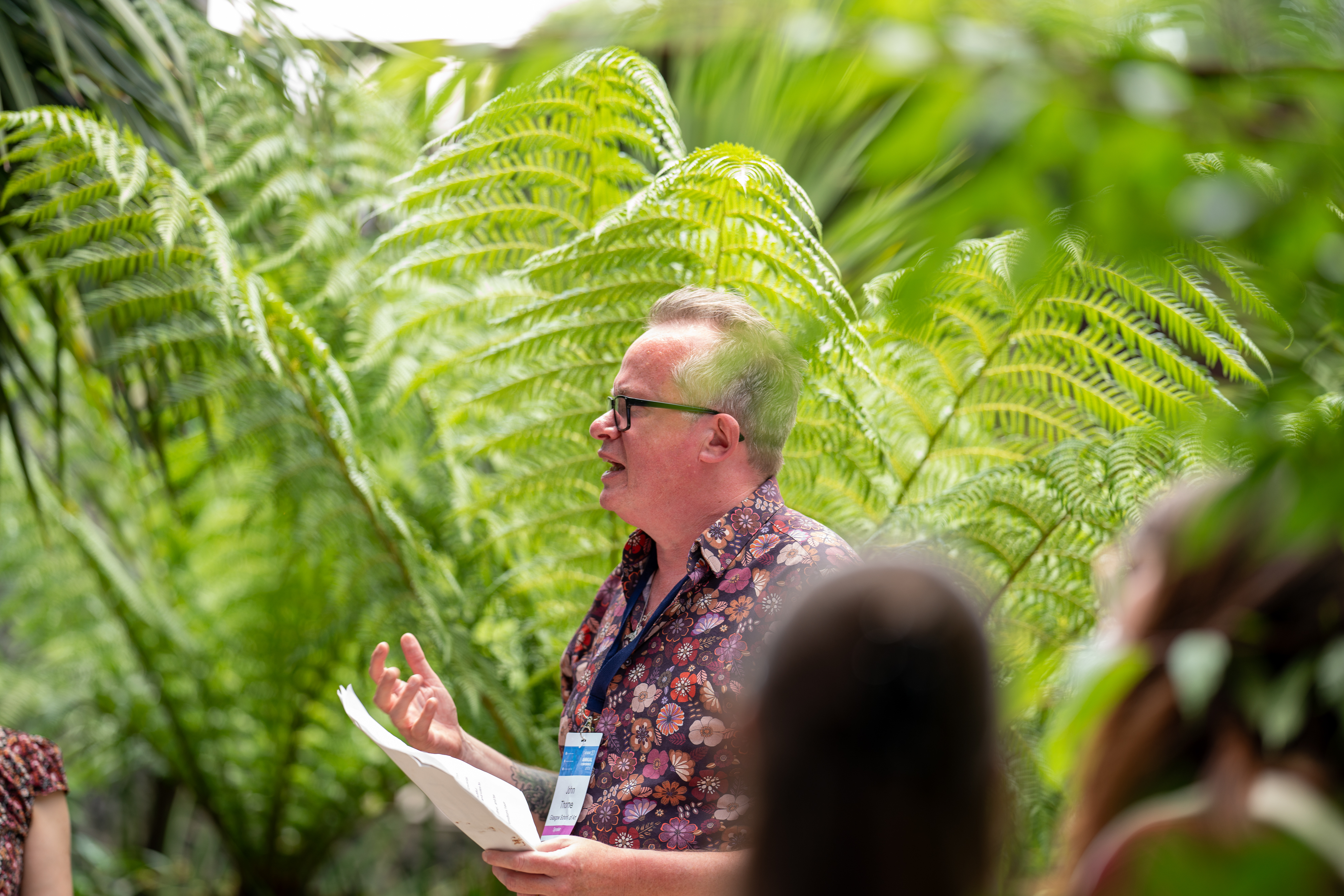A man stands in front of a lush green palm tree 