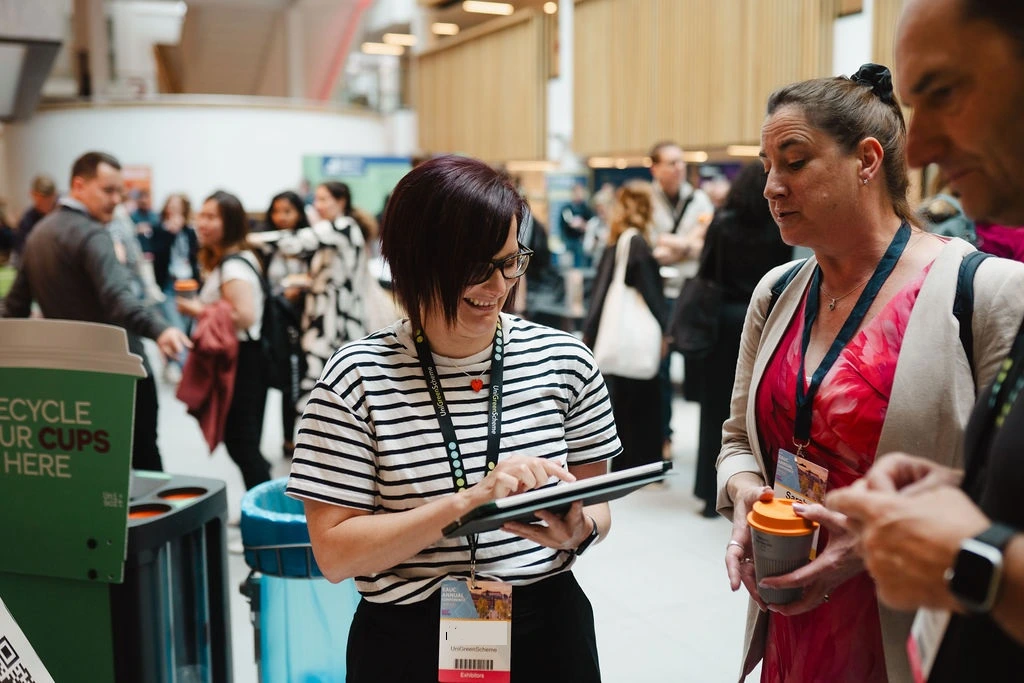 A woman wearing a stripey top and lanyard takes information through an ipad at an EAUC conference