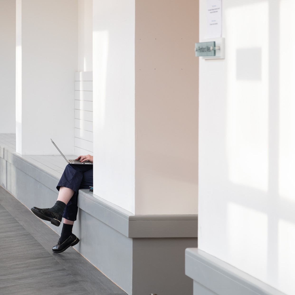 A person using their laptop in a hallway. 