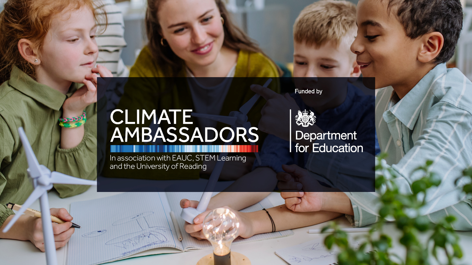 A woman surrounded by children look at a model wind turbine in a classroom. Text reads Climate Ambassadors funded by the Department of Education. 