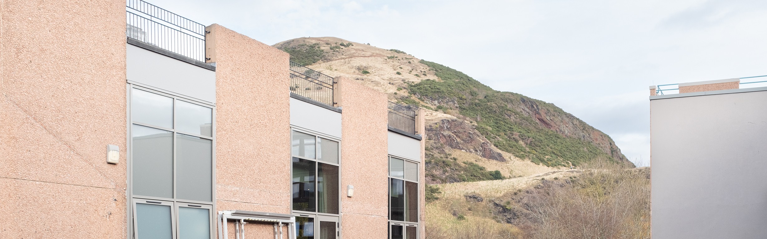A university building with a view of a hillside in the background. 