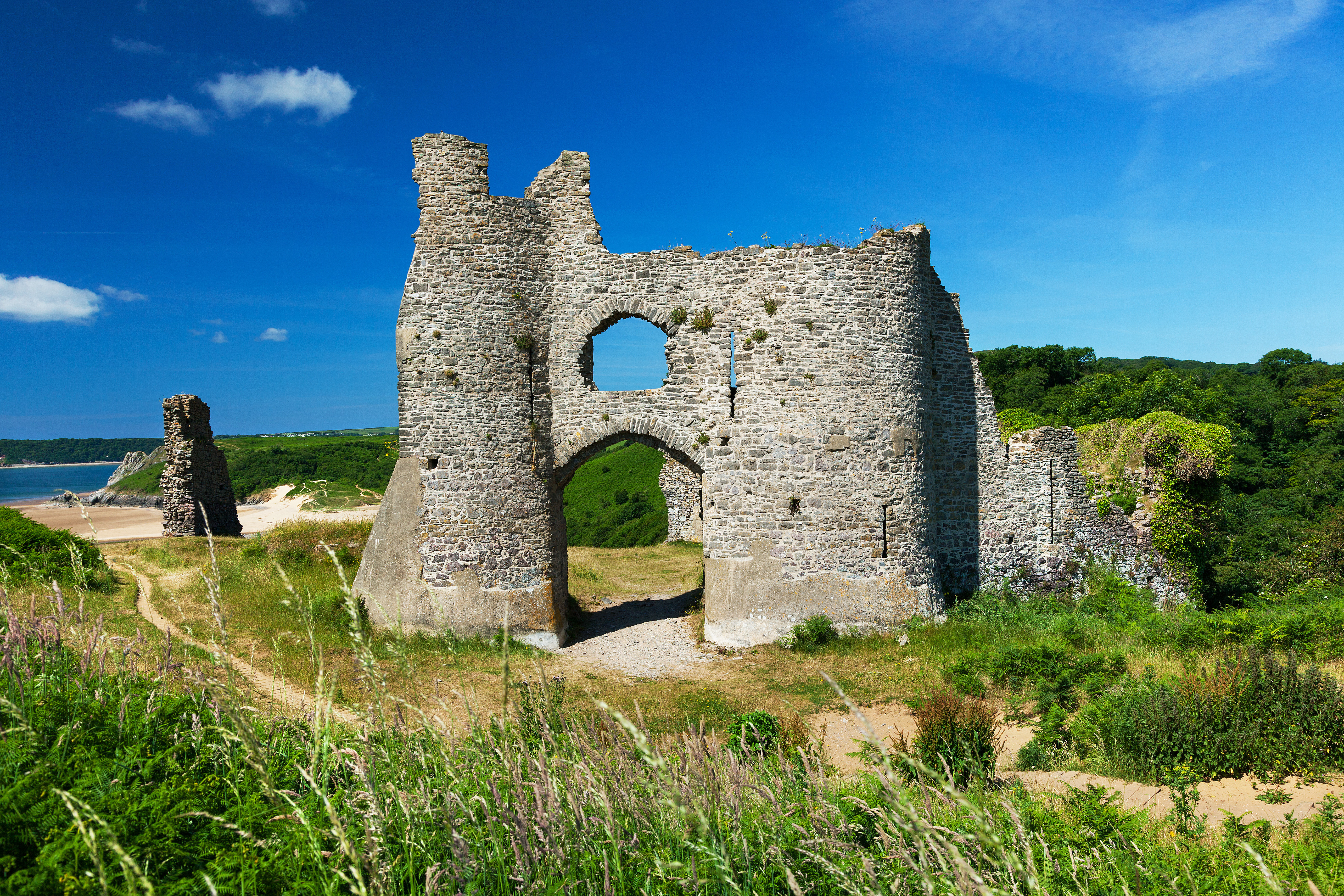 A bright blue sky with a few colours with an old ruined castle in the foreground