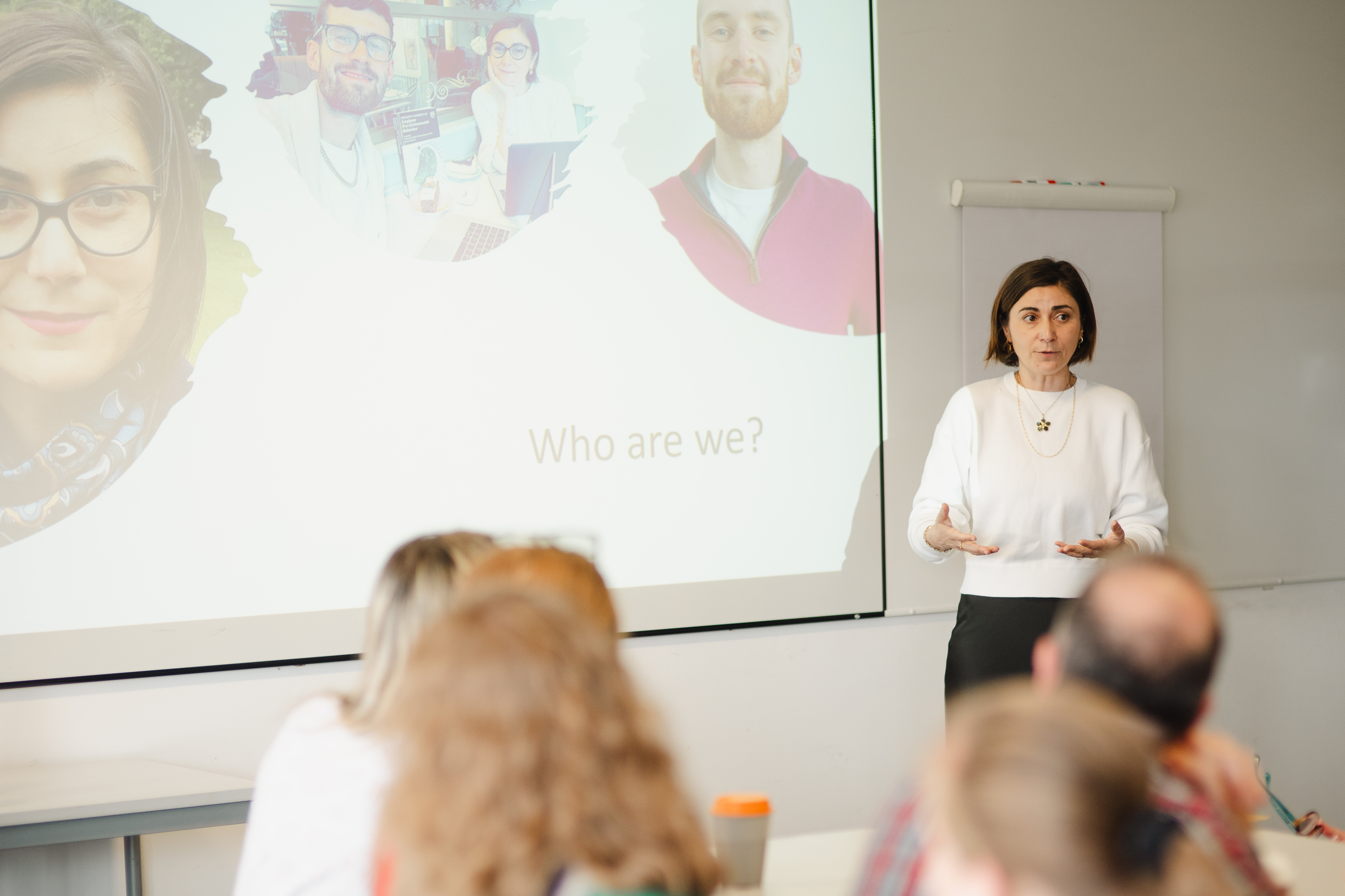 A person presenting to a classroom with slides projected behind them.